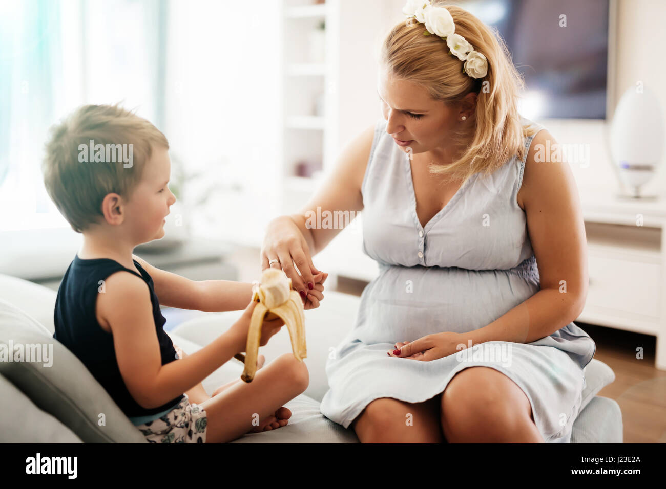 Schöne Mutter kuscheln Kind während eine Banane earing Stockfoto
