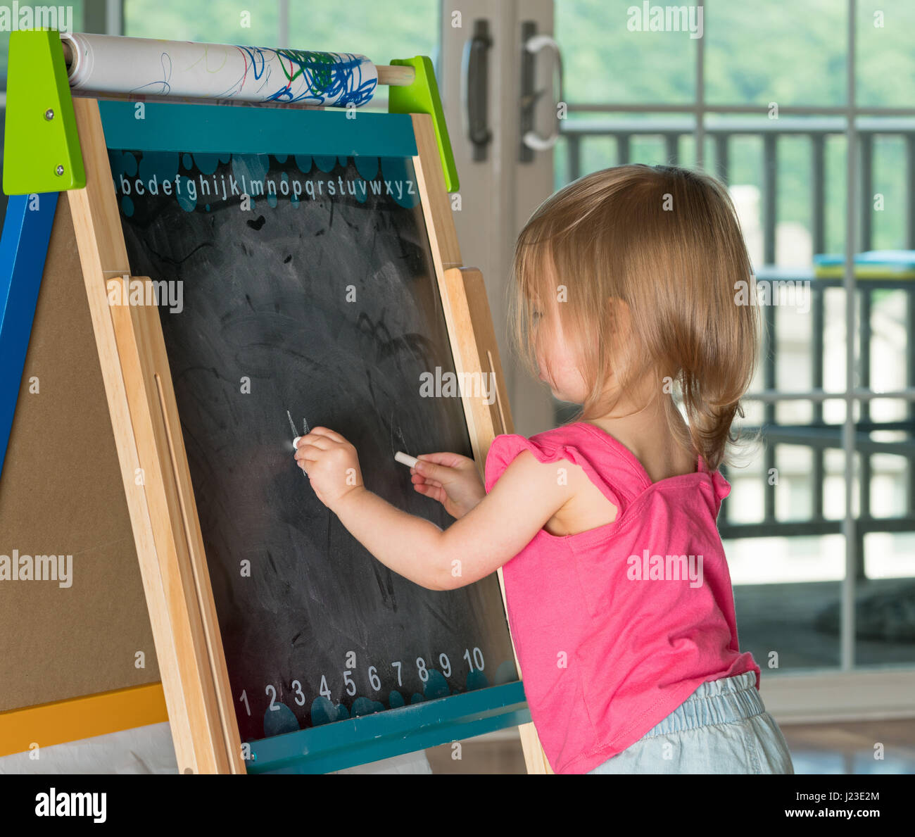 Junge Kind schreiben lernen und Schreiben mit Kreide auf einer Tafel Stockfoto