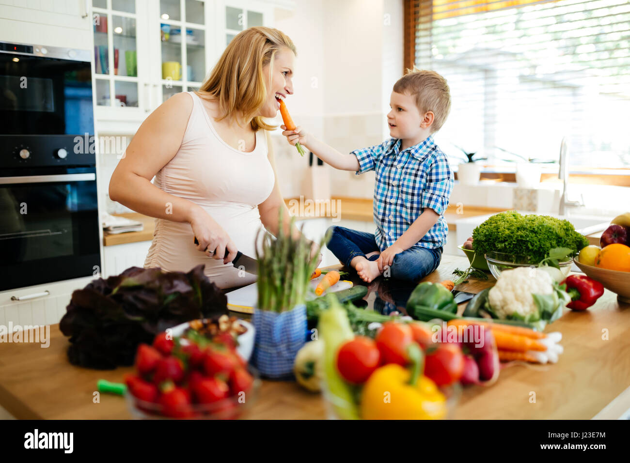 Schwangere Frau mit Sohn aus frischem Gemüse Zubereitung Stockfoto