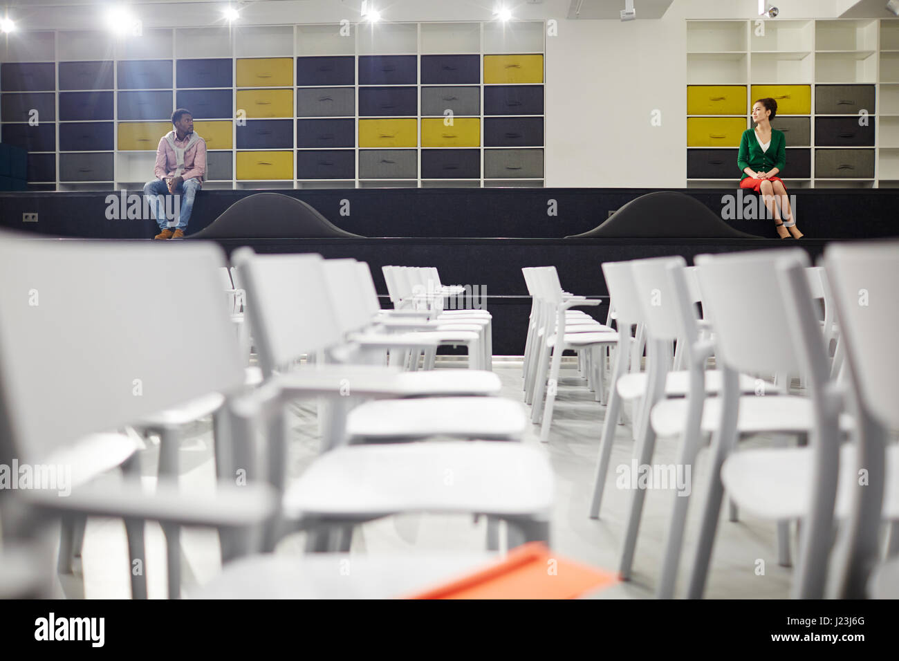 Junger Mann und Frau einander betrachten, beim Sitzen auf der großen Treppe im Konferenzsaal Stockfoto