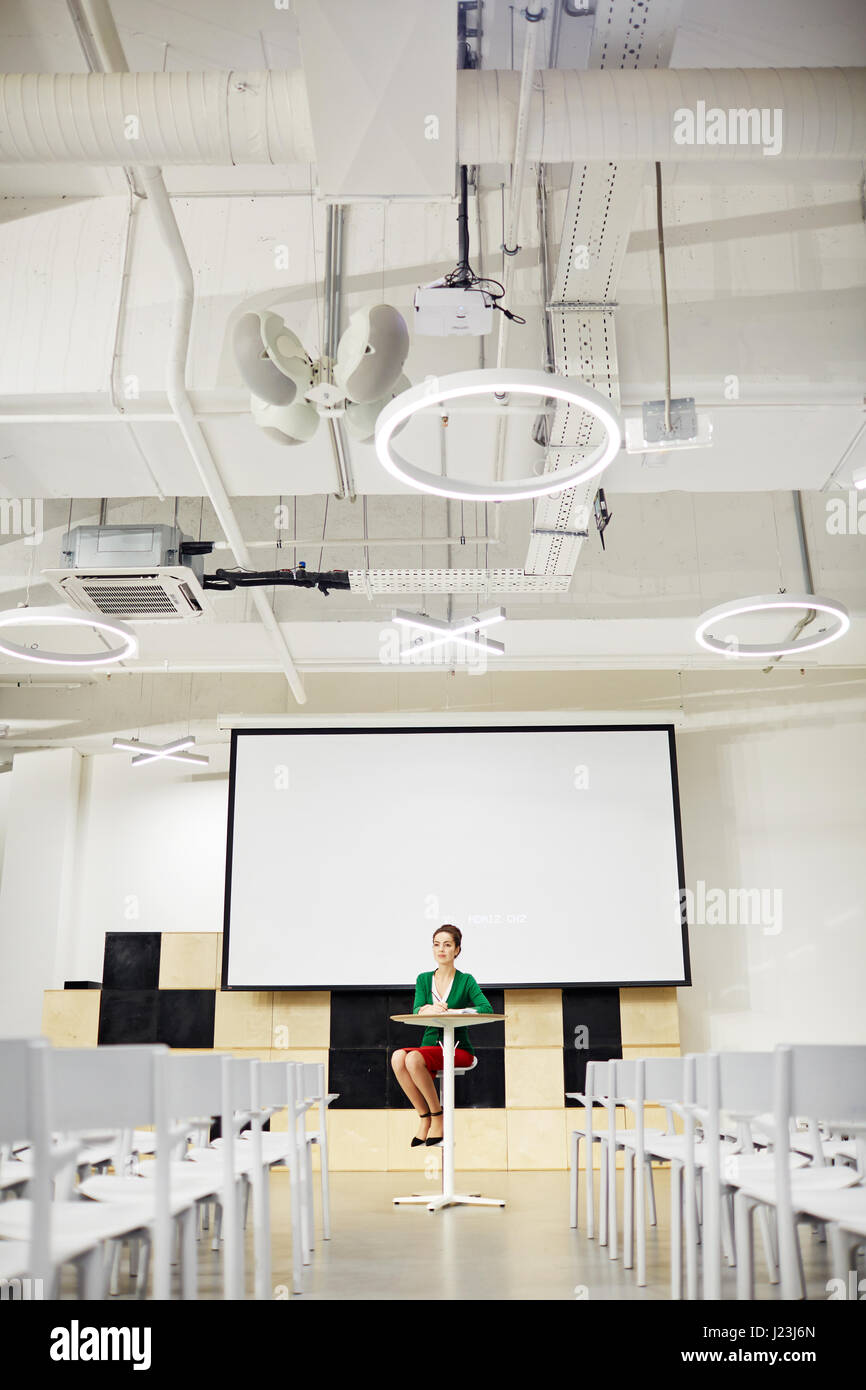 Junge Frau mit Whiteboard hinter sitzen im Hörsaal Stockfoto