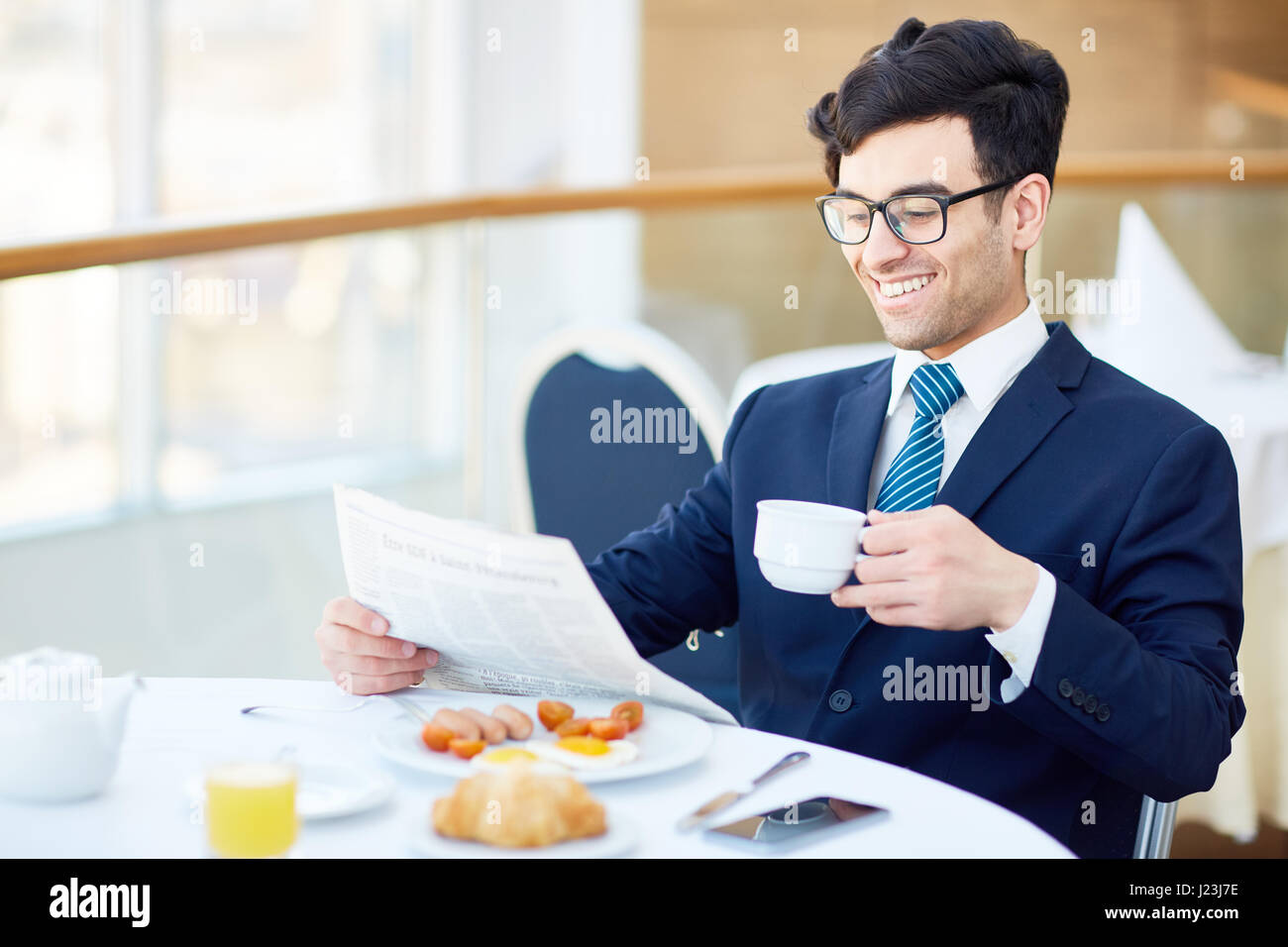 Lächelnde Geschäftsmann Tee oder Kaffee trinken und Zeitung im café Stockfoto