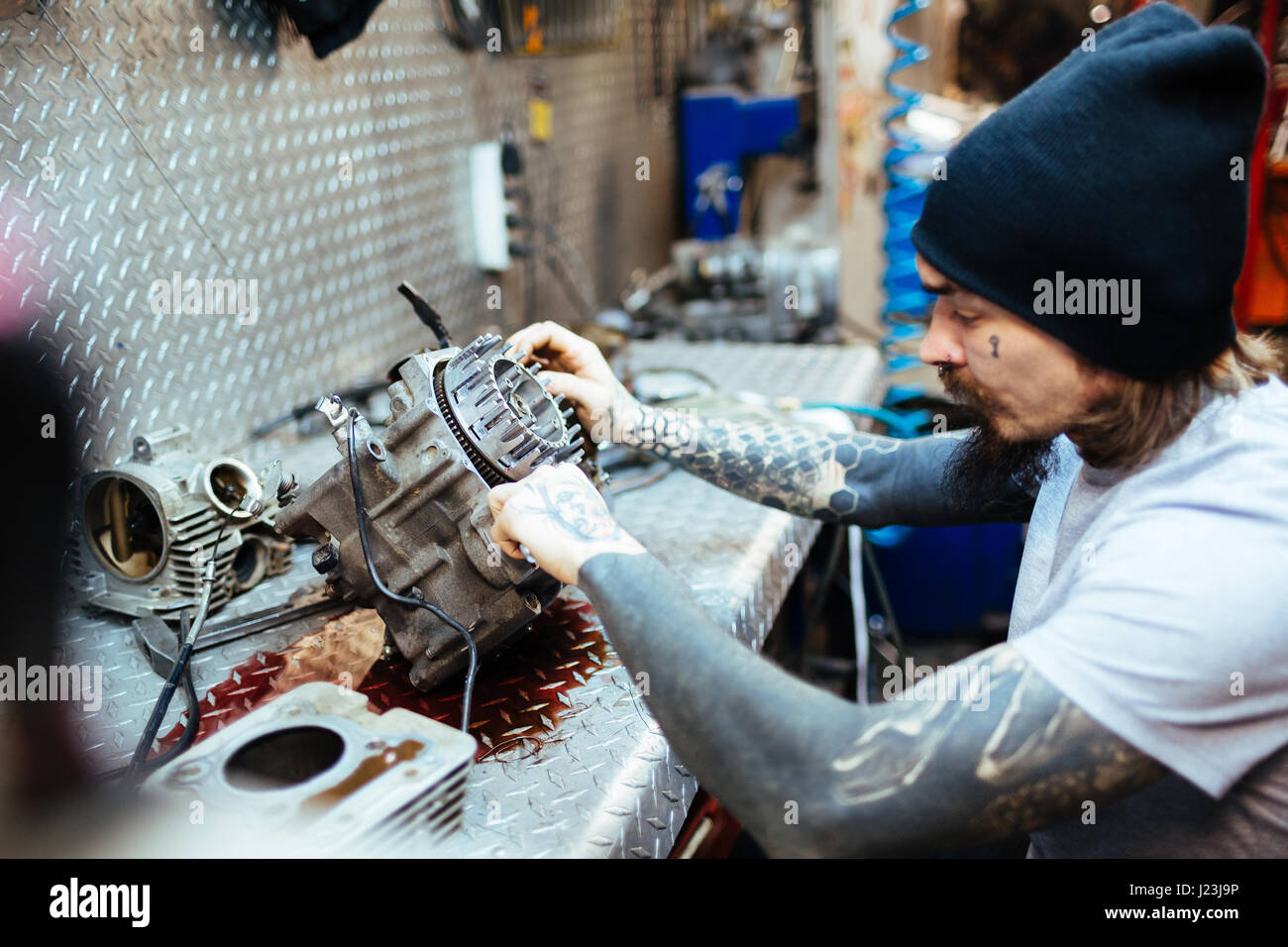 Seite Ansicht Porträt des modernen tätowierte Menschen defekten Motor Befestigungsteile in Werkstatt Stockfoto