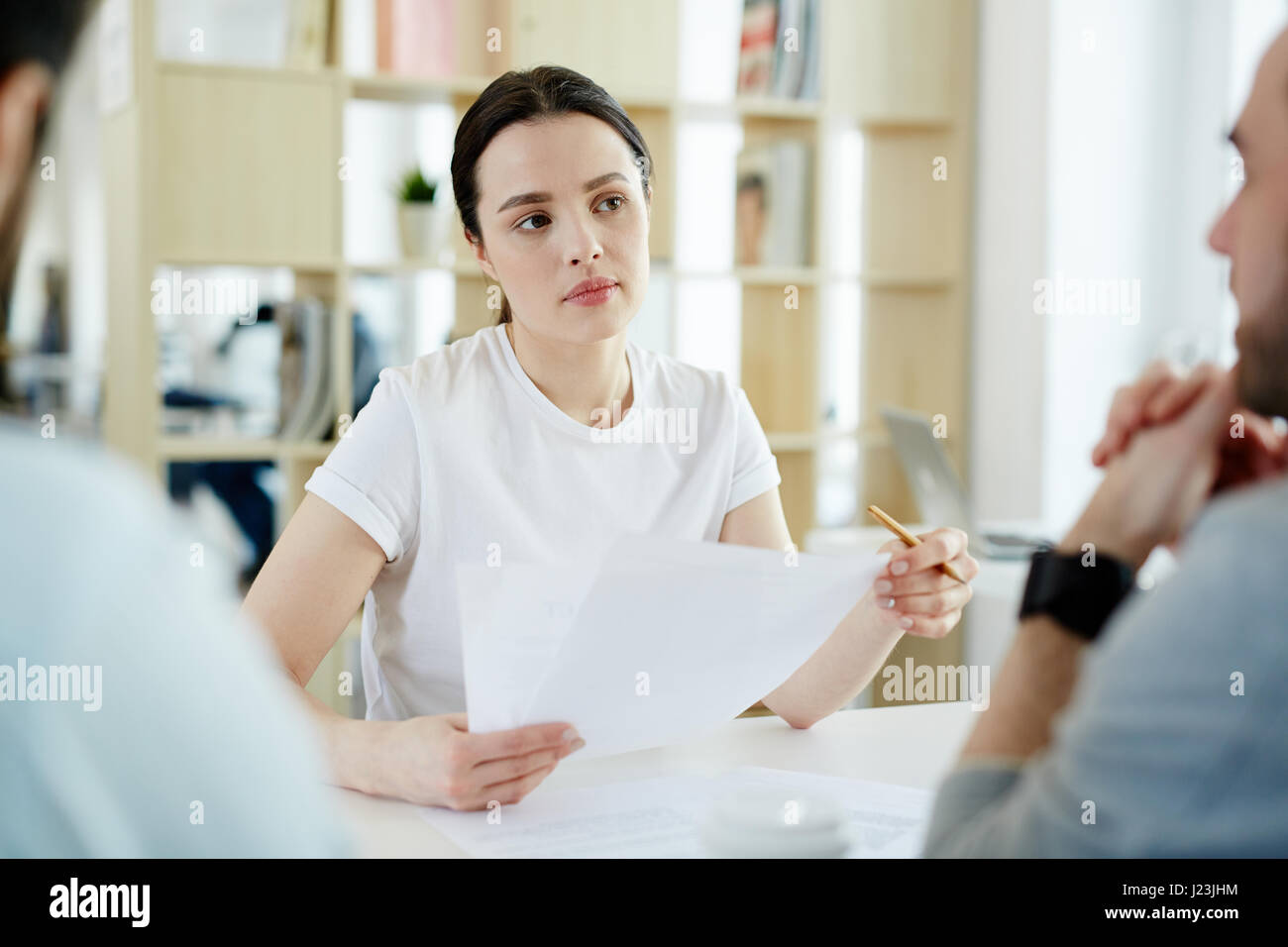 Porträt der jungen Frau lauschte während der Diskussion Geschäft mit zwei Männern während der Sitzung im modernen Büro Stockfoto