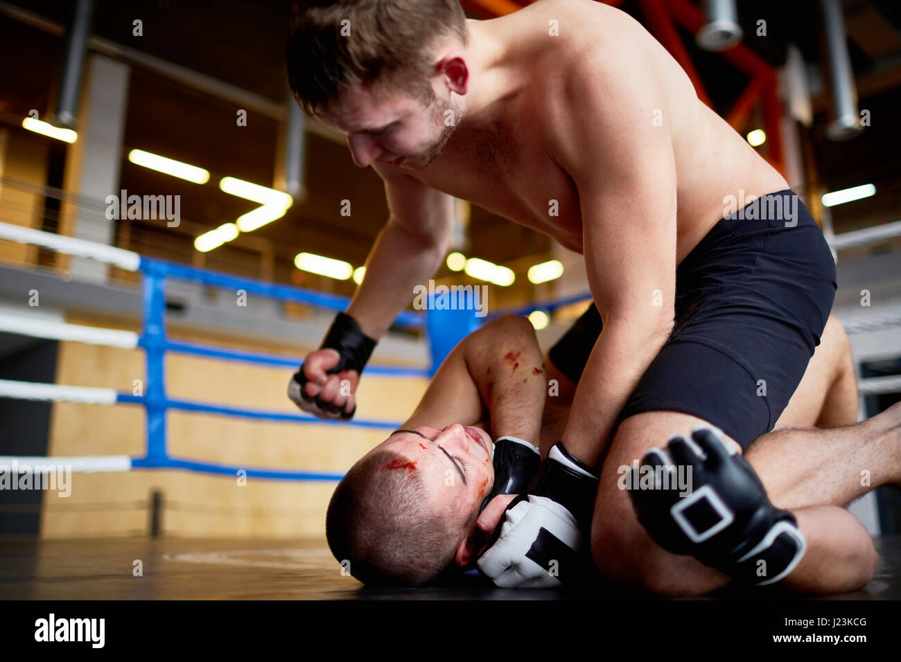 Porträt der Wrestler kämpfen im Boxring: Mann schlagen blutigen Gegner im Kampf gegen ihn zu Boden Gesicht Stockfoto