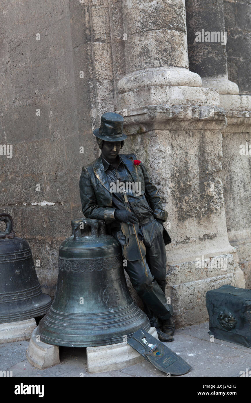 Lebende Statue in Havanna in der Nähe von Bronze-Skulptur von Glocken. Stockfoto