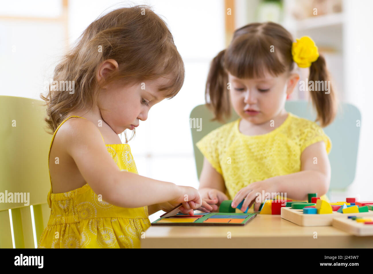 Kinder spielen mit logischen Spielzeug auf Schreibtisch im Kinderzimmer oder im Kindergarten. Kinder ordnen und sortieren, Formen, Farben und Größen. Stockfoto