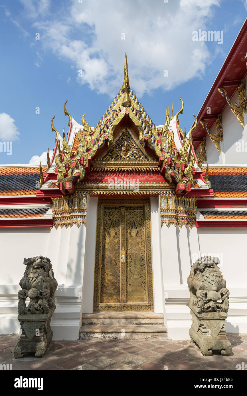 Zwei Statuen vor einem geschmückten Tür und Tor an der Tempelanlage Wat Pho (Po) in Bangkok, Thailand. Stockfoto