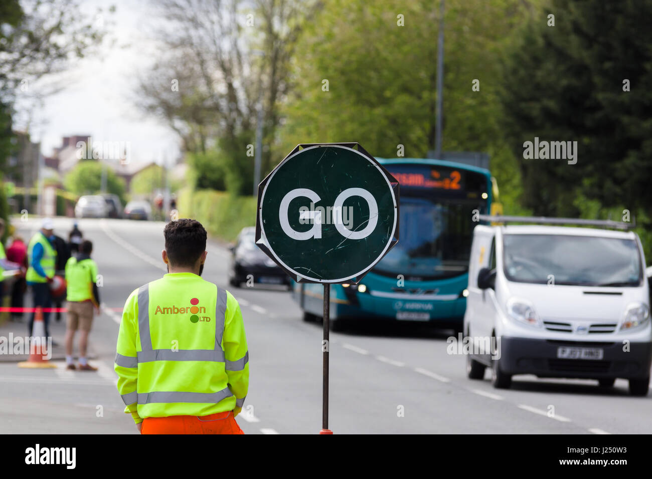 Manuell gesteuertes „Stop Go“-Schild für temporäre Straßenarbeiten, das zur Verkehrskontrolle auf einer stark befahrenen Stadtstraße in Chirk Wales verwendet wird Stockfoto