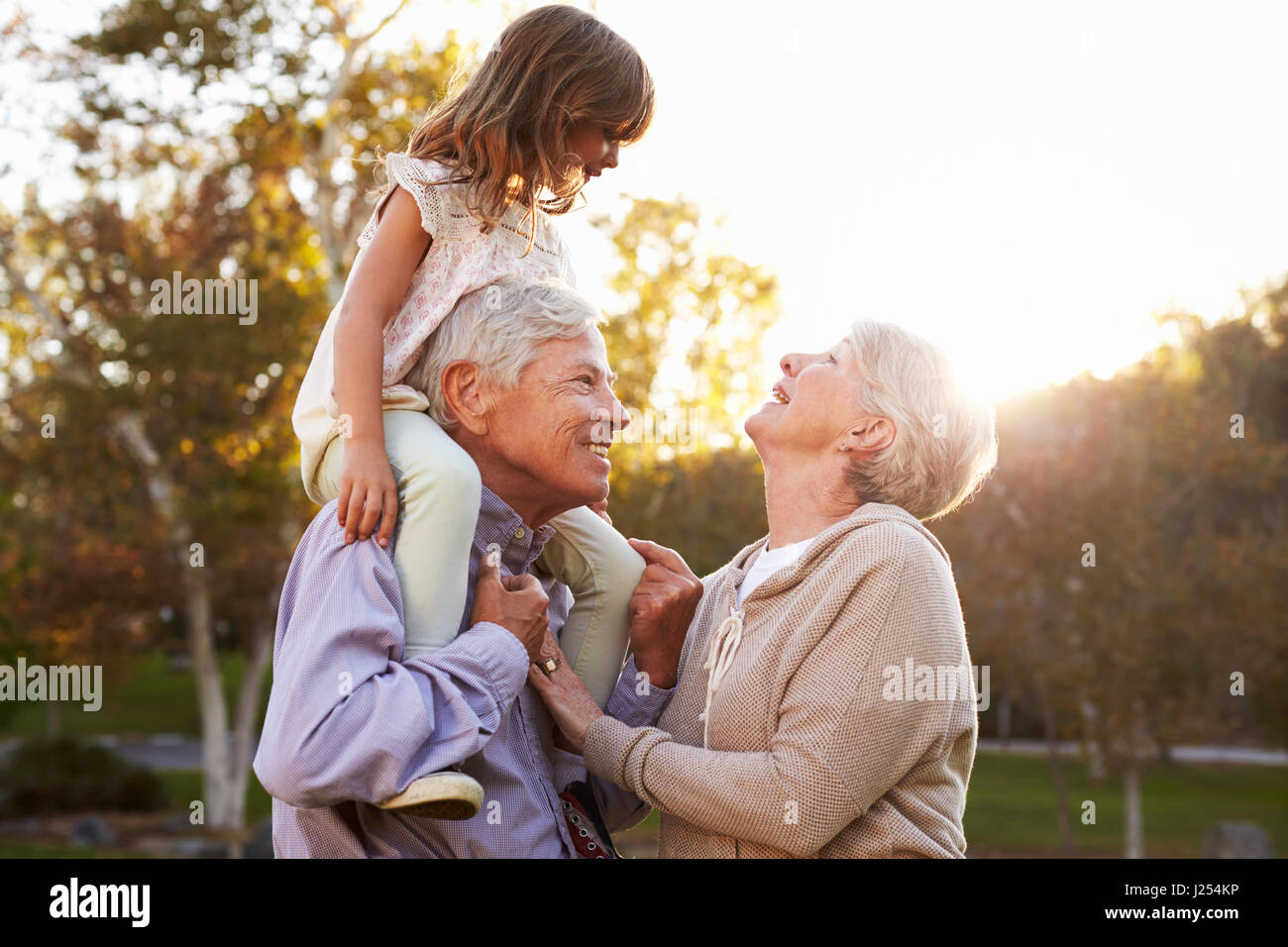 Großeltern geben Enkelin A Schulter fahren im Park Stockfoto