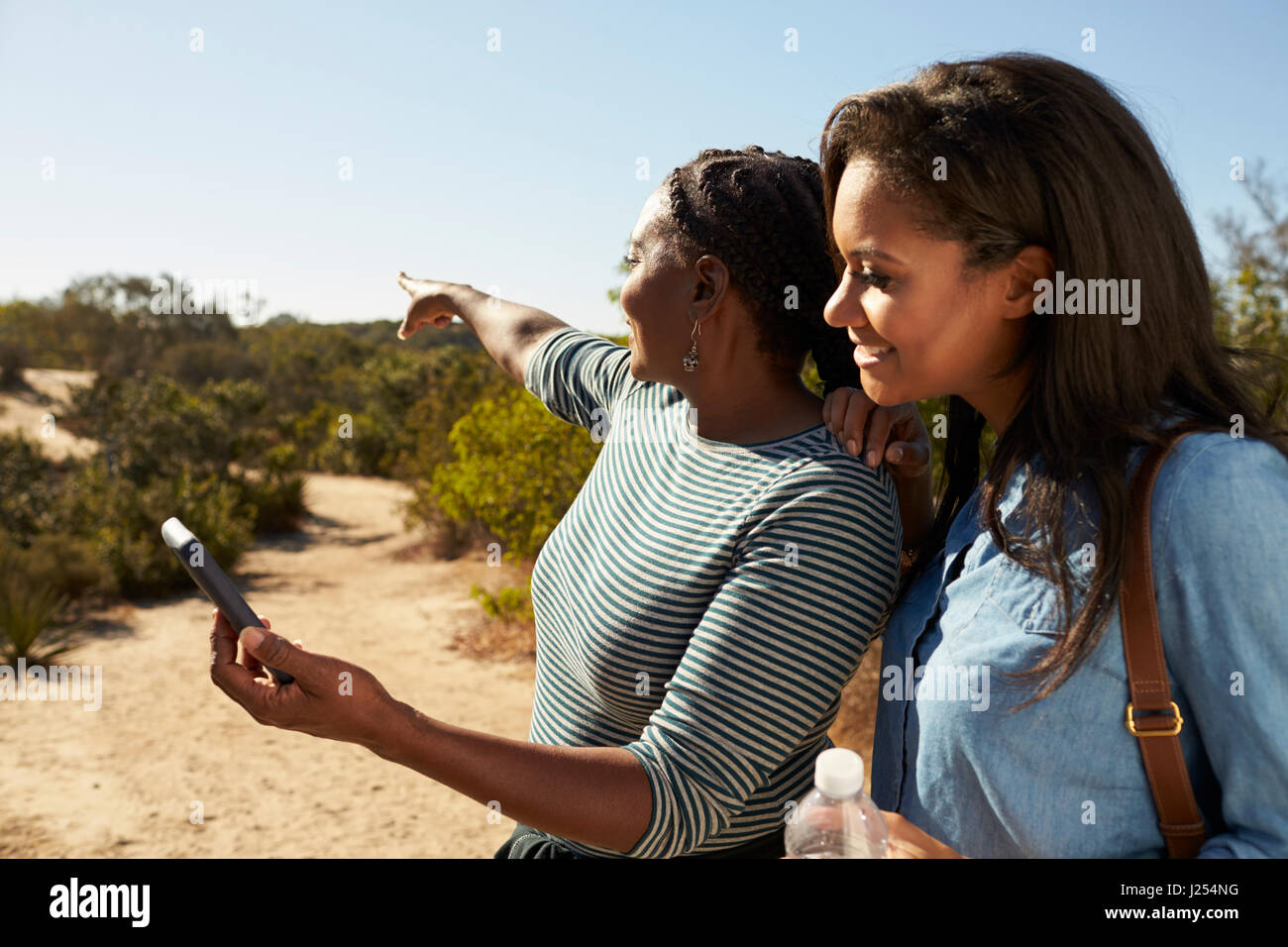 Mutter und Erwachsene Tochter navigieren mit Handy auf Spaziergang Stockfoto