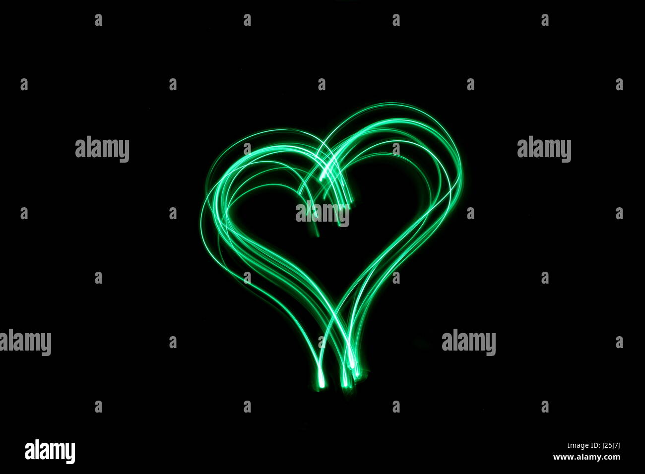Lange Belichtung Foto von Neon Grün Farbe in einem Herzen Umriss der Form vor einem schwarzen Hintergrund. Licht Malerei Fotografie, abstrakte Farbe Stockfoto