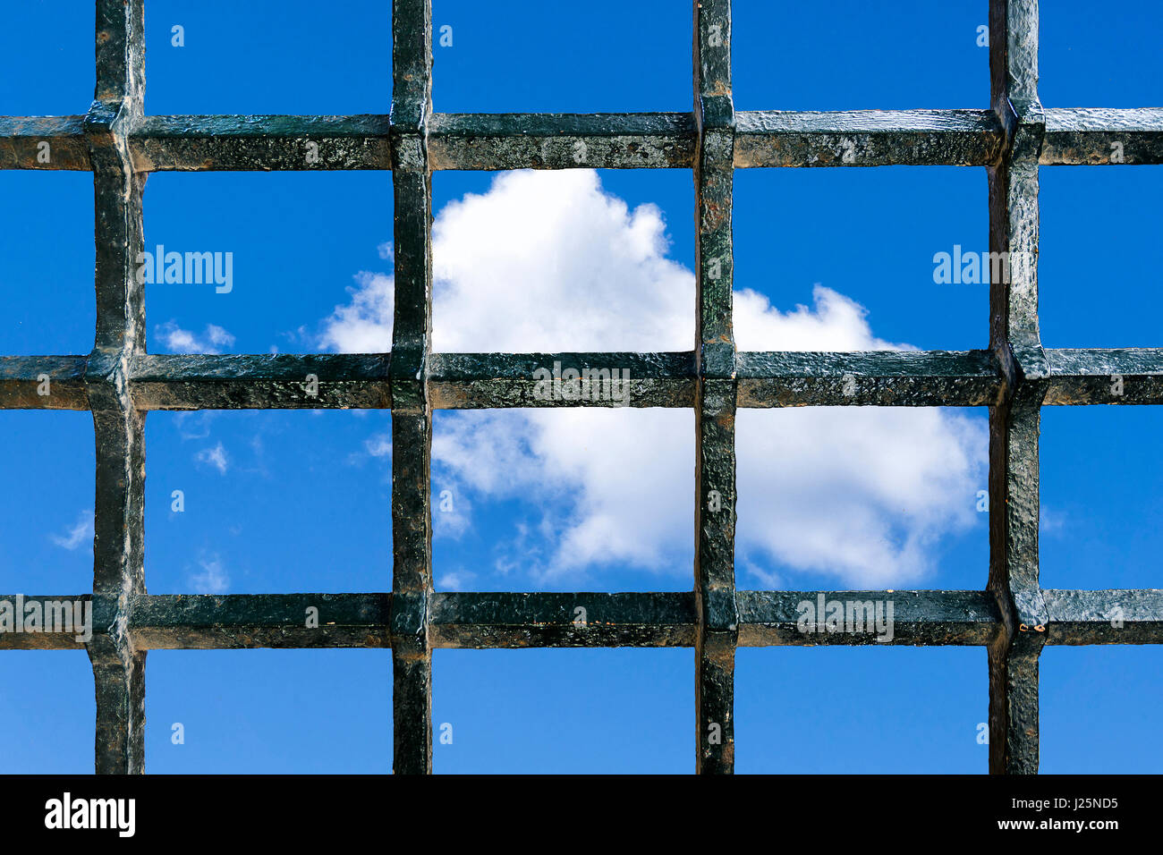 Metall-Gefängnis Bars mit einem blauen Himmel mit Wolken im Hintergrund als ein Konzept der Freiheit Wunsch Stockfoto