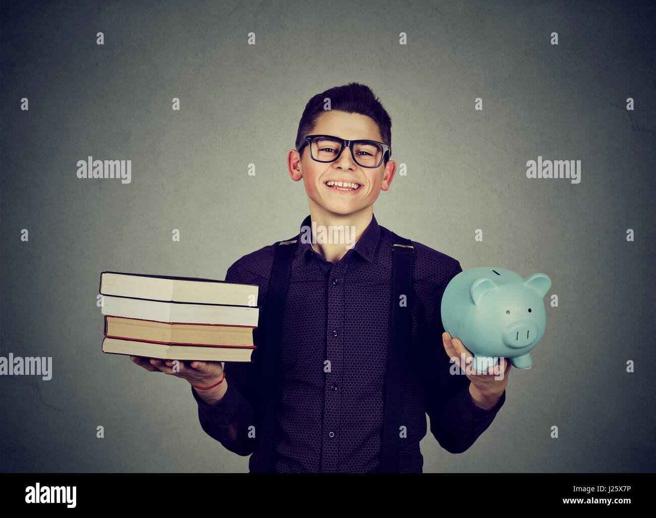 Student Loan Konzept. Glücklicher Mann mit Stapel Stapel von Büchern und Sparschwein voller Schulden Stockfoto