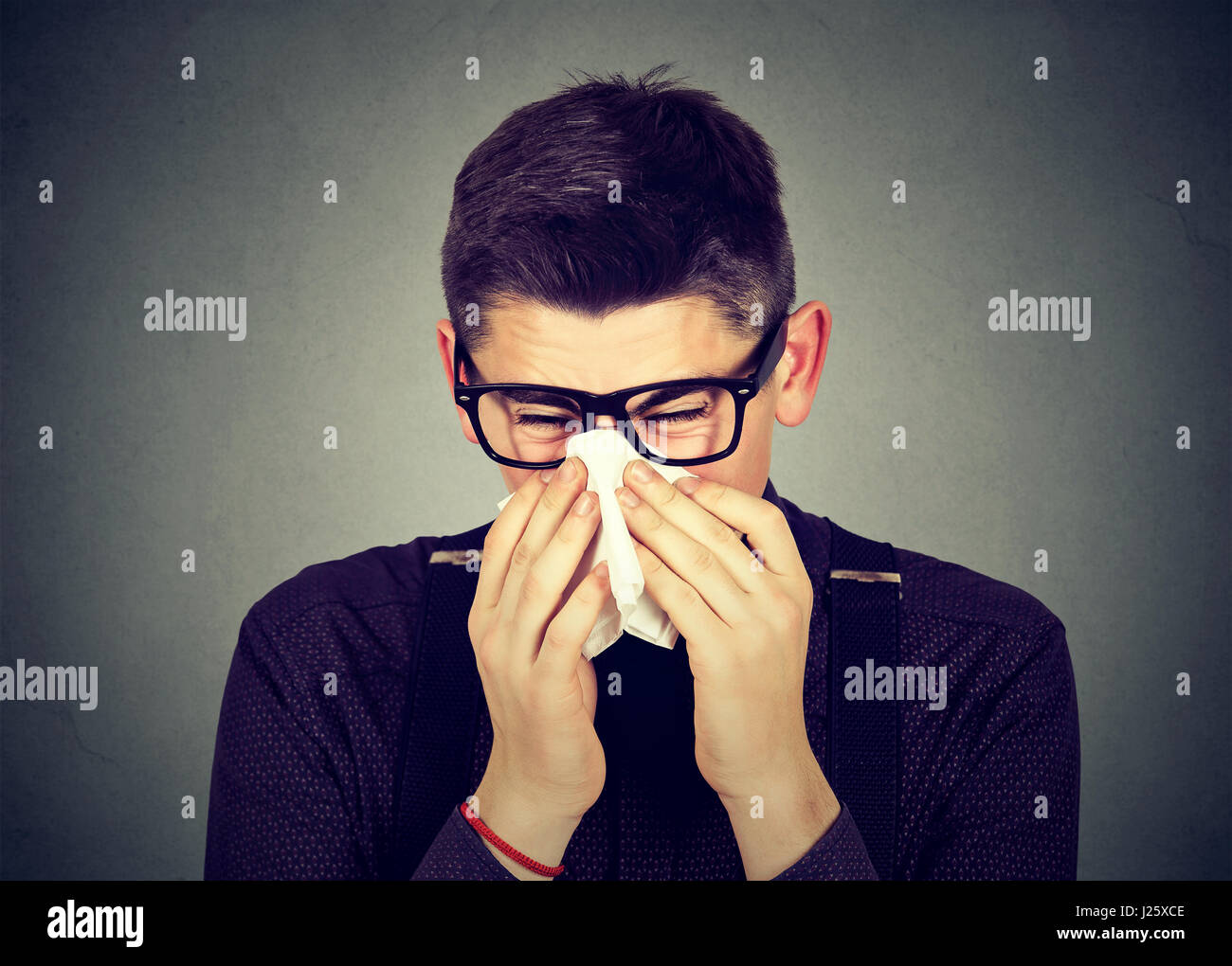 Junger Mann in Gläser in einem Gewebe bläst seine laufende Nase niesen Stockfoto