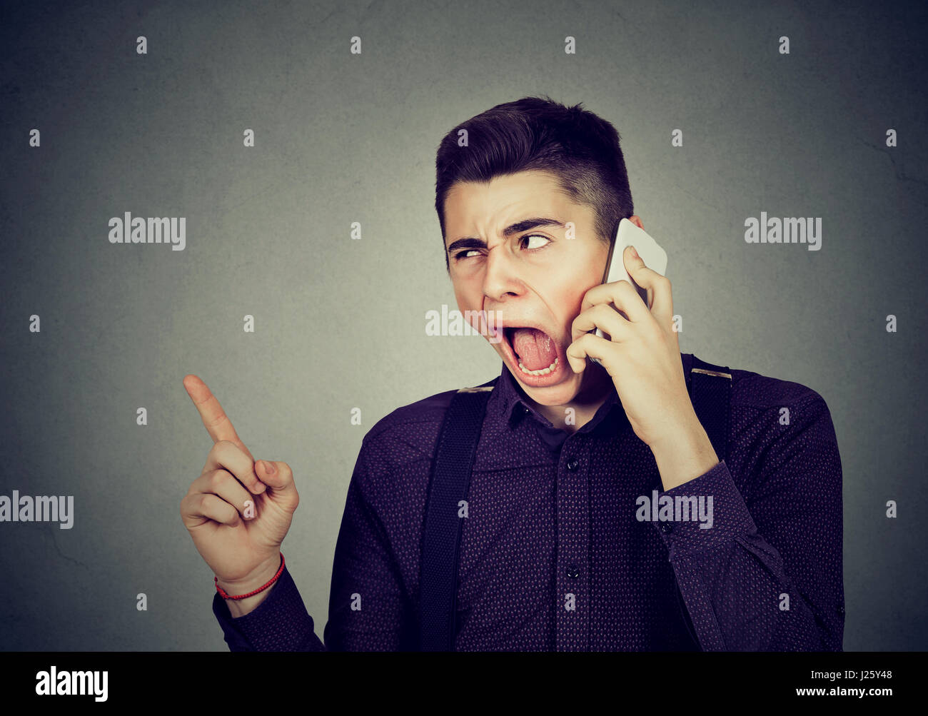 zorniger junger Mann schreien auf Handy Stockfoto
