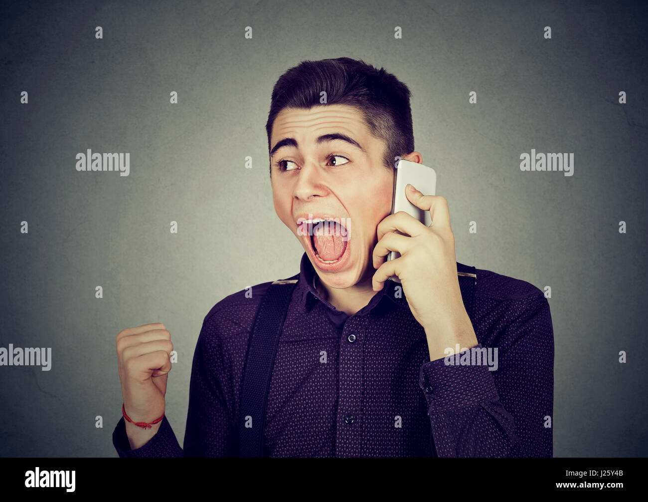 zorniger junger Mann schreien auf Handy Stockfoto