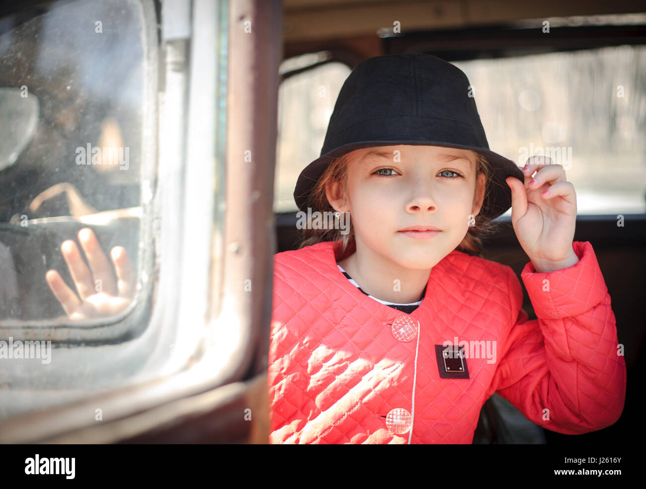 Porträt der ein kleines Mädchen mit einem schwarzen Hut in einem Retro-Auto. Stockfoto
