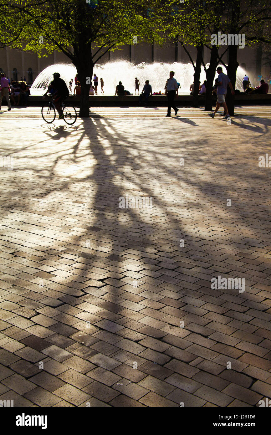 Stadtpark-Szene mit Brunnen und lange Schatten werfen auf Brick Plaza Stockfoto