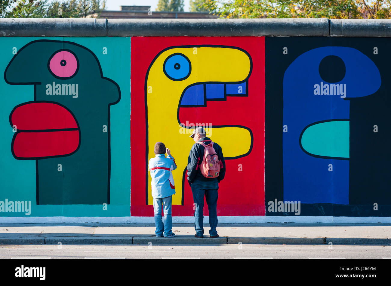 Touristen, die gerne am Wandbild auf Berliner Mauer an der East Side Gallery in Berlin Deutschland Stockfoto