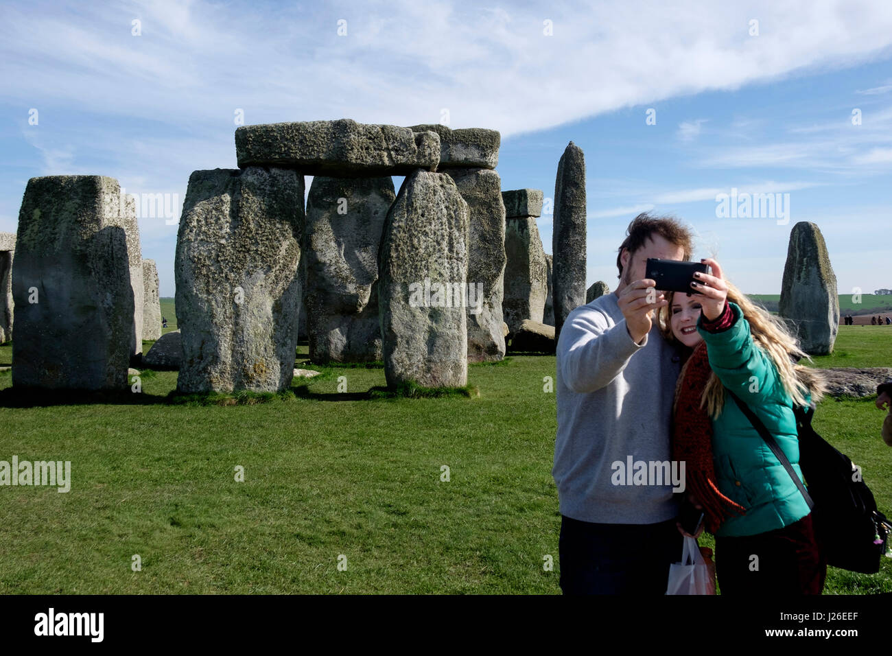 Junge Frau, die eine Selfie mit ihrem Smartphone vor dem prähistorischen Monument von Stonehenge in Wiltshire, England Stockfoto