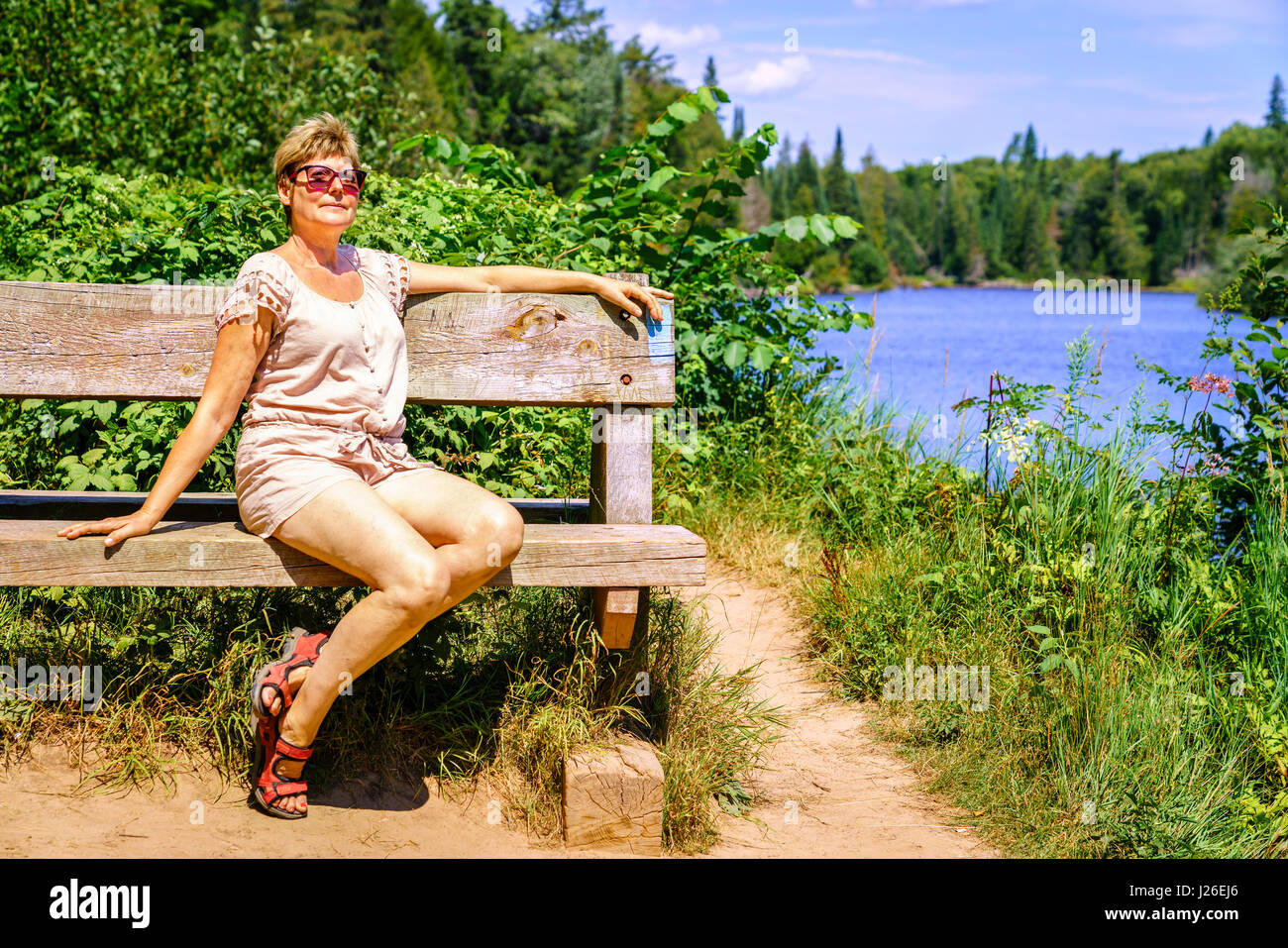Porträt einer Frau entspannen Sie sich auf eine Bank in der Nähe von Fluss Stockfoto