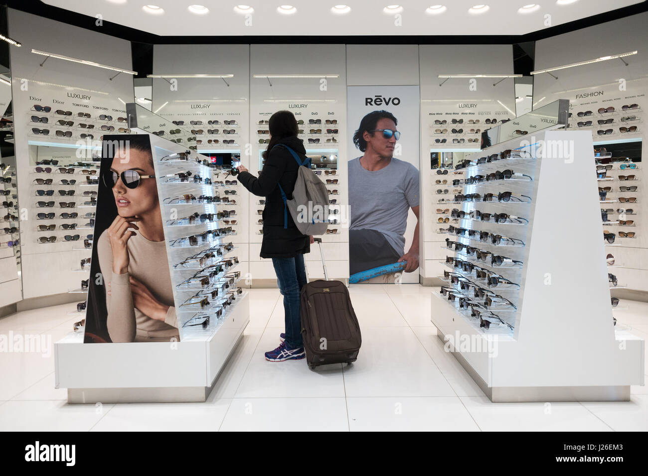 Frau mit Gepäck Einkaufen für Sonnenbrillen am Tax free shop im Flughafen Stockfoto