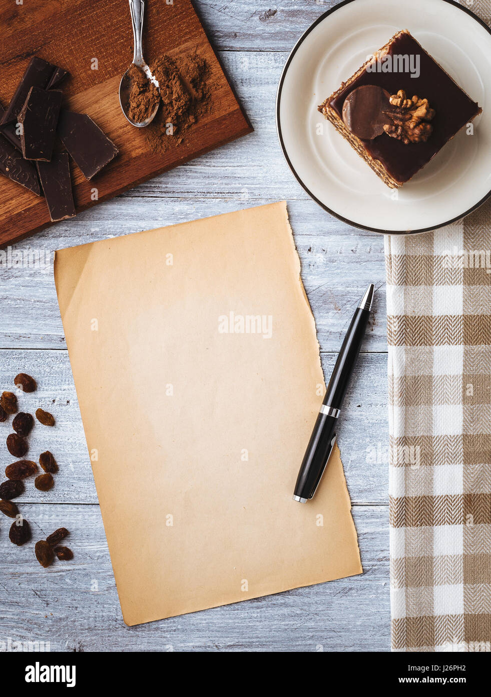 Hausgemachter Schokoladenkuchen und alte Blankopapier für Rezept auf Holztisch. Getönten Foto. Ansicht von oben. Stockfoto