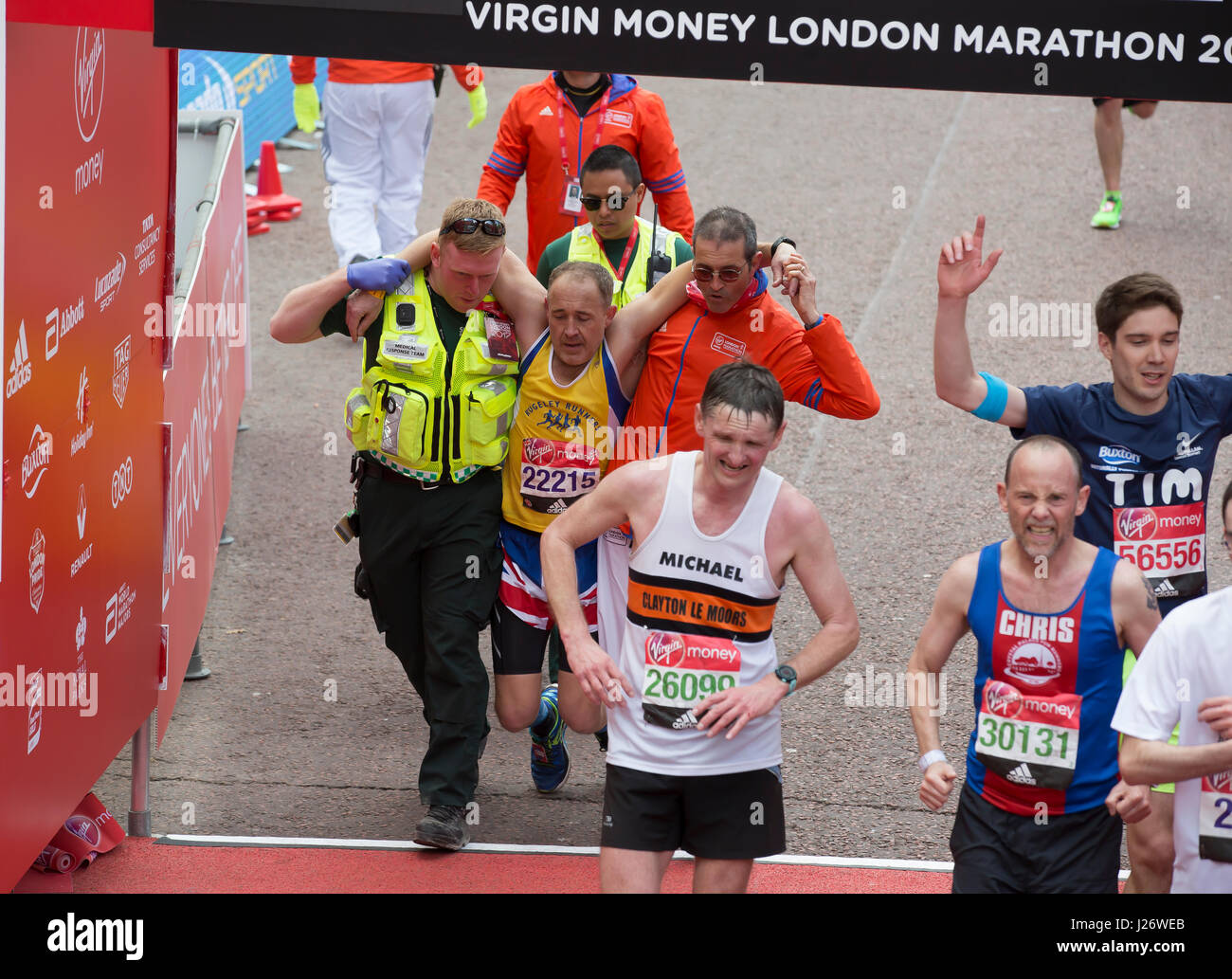 Ein Mann muss über die Linie Virgin London Marathon zu beenden, in der Mall geholfen werden Stockfoto