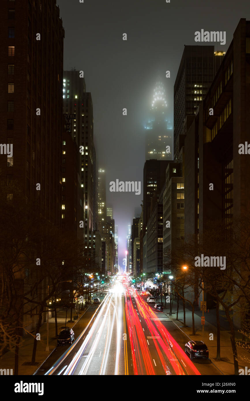 Die Aussicht von Tudor Stadt in Richtung das Chrysler Building bei Nacht, die teilweise in der Wolke ist, Auto Licht Wanderwege auf der Straße gesehen werden kann, Neue Stockfoto