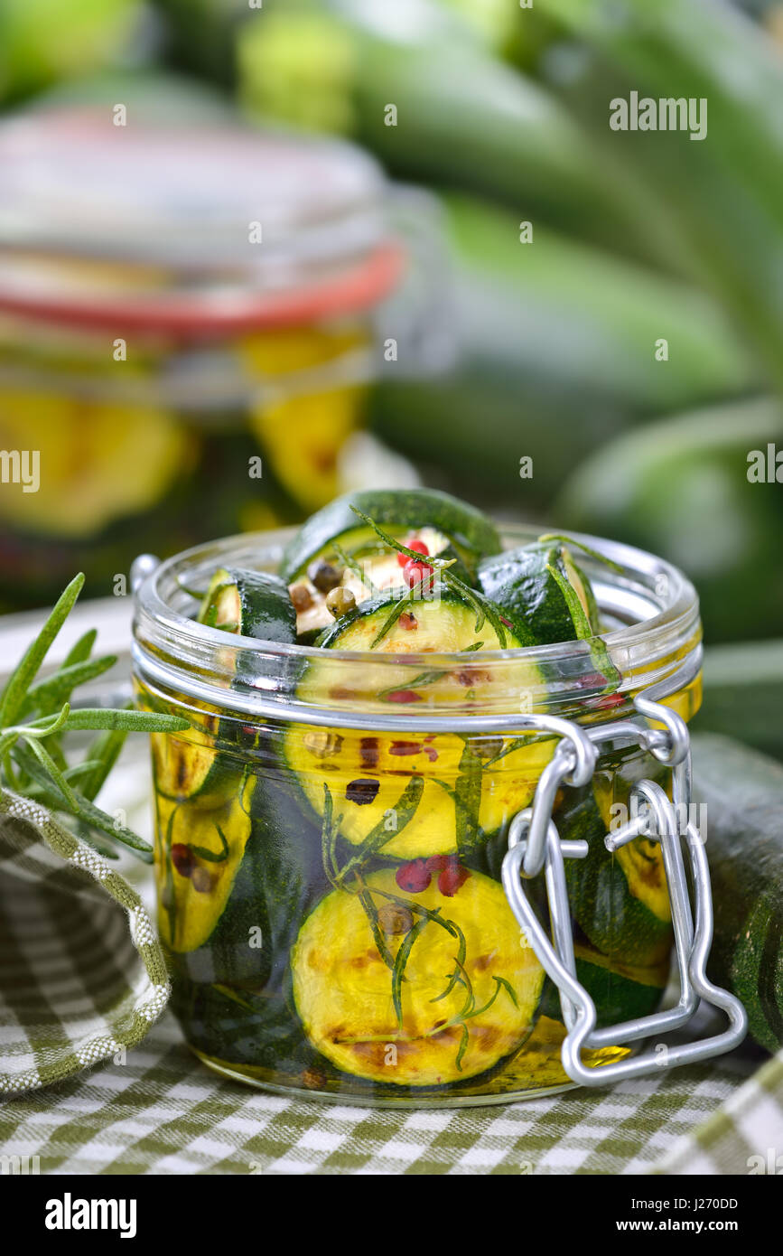 Gebratene Zucchinischeiben eingelegt in Olivenöl mit Kräutern und in Konserven Glas gefüllt Stockfoto