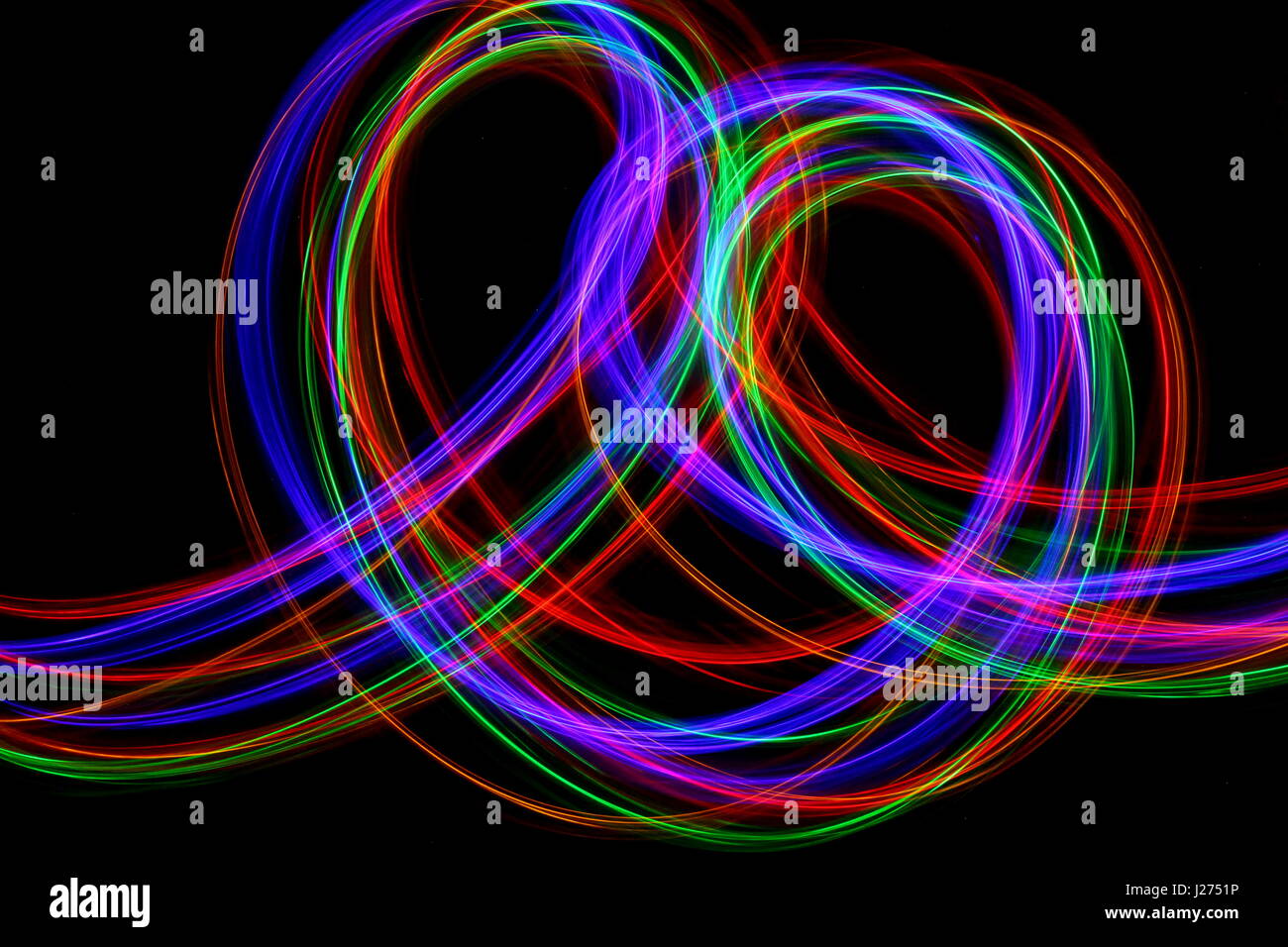Lange Belichtung Foto von Neon multi-color in einer abstrakten wellenförmige Muster vor einem schwarzen Hintergrund. Licht Malerei Fotografie, abstrakte Farbe Stockfoto