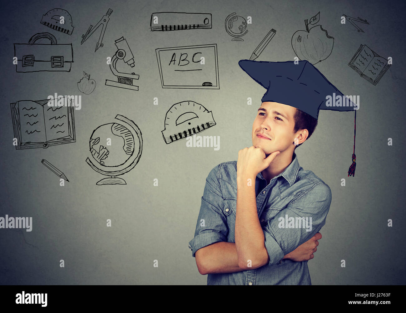 Schönen jungen Mann mit Graduierung Hut nachschlagen Nachdenken über Bildung auf graue Wand Hintergrund isoliert Stockfoto