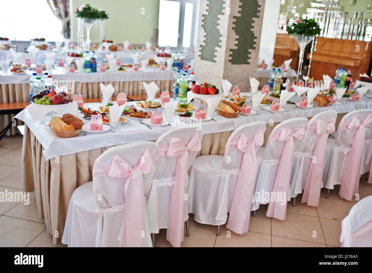 Stühle mit rosa Schleife im Hochzeitssaal. Stockfoto