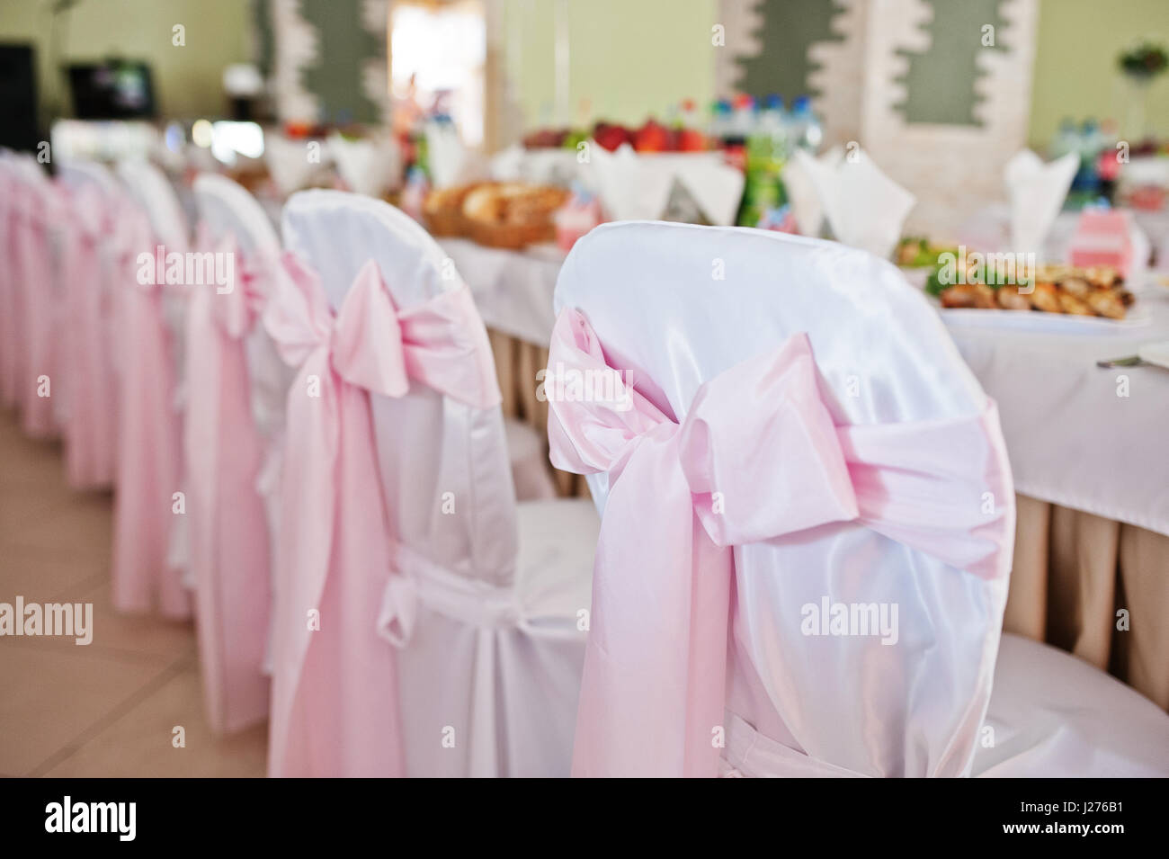 Stühle mit rosa Schleife im Hochzeitssaal. Stockfoto