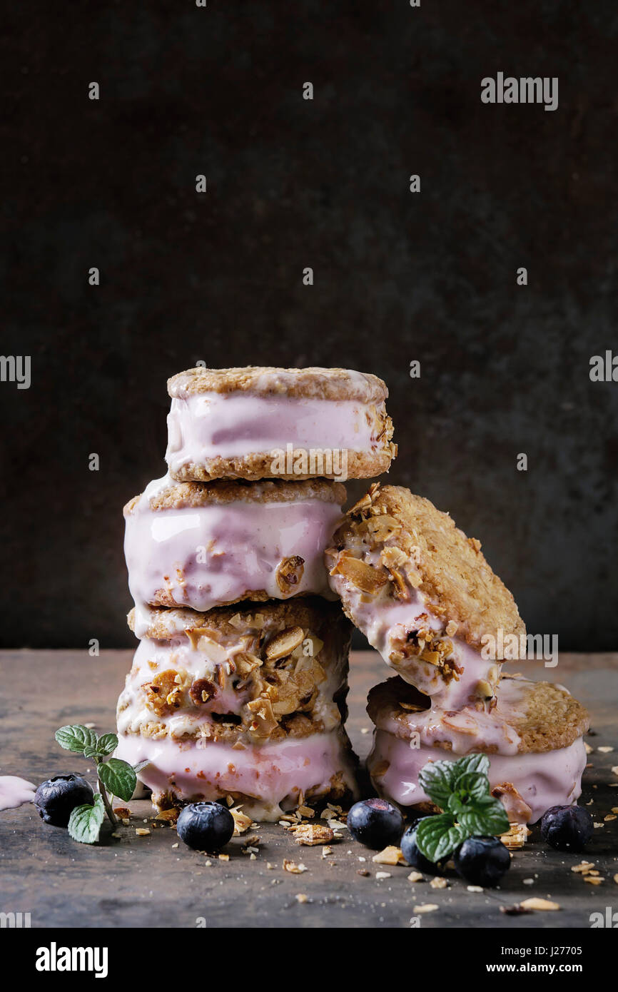 Satz von hausgemachte Blueberry Ice Cream sandwiches in Hafer-Kekse mit Mandeln Zucker Krümel, Blaubeeren und Minze über dunkle Metall Textur Hintergrund. In der Nähe Stockfoto
