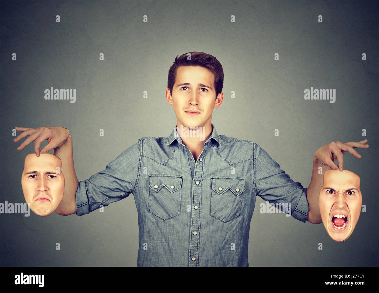 Lächelnder Mann hält zwei verschiedene Gesichtsmasken emotion Stockfoto