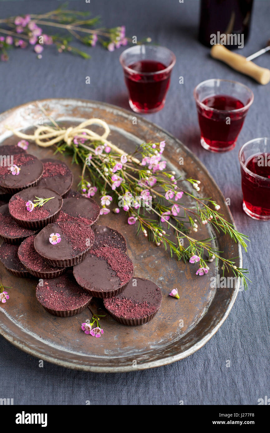 Marzipan-Hibiscus-Tassen serviert auf einem Kupfertablett mit Dessertwein. Phototgraphed auf eine graue Tischdecke. Stockfoto