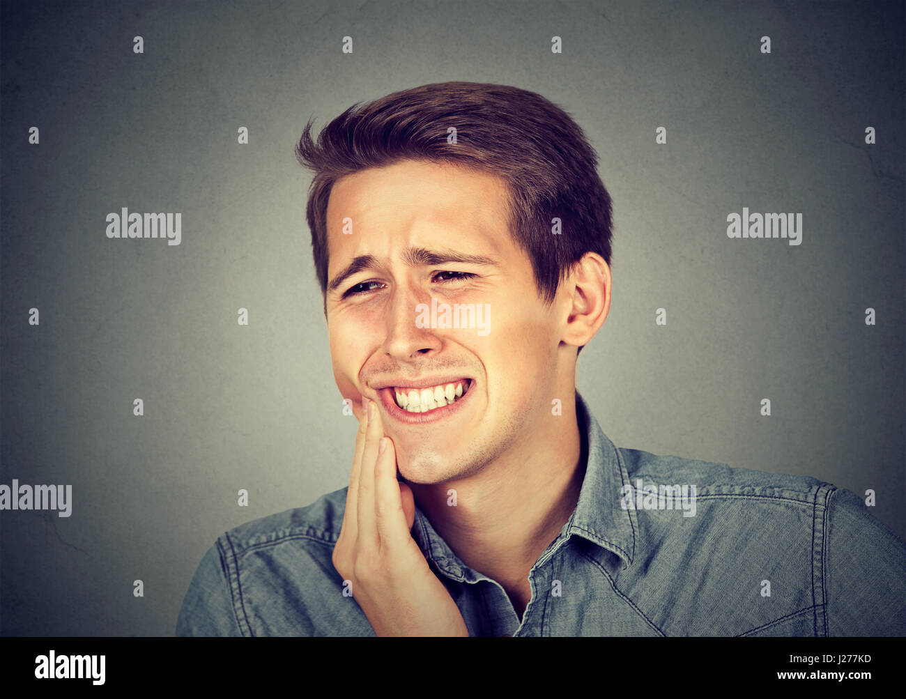 Closeup Portrait junger Mann mit sensiblen Zahnschmerzen Krone Problem zu Weinen vom Schmerz berührt außen Mund mit der Hand auf grauem Hintergrund isoliert. Stockfoto