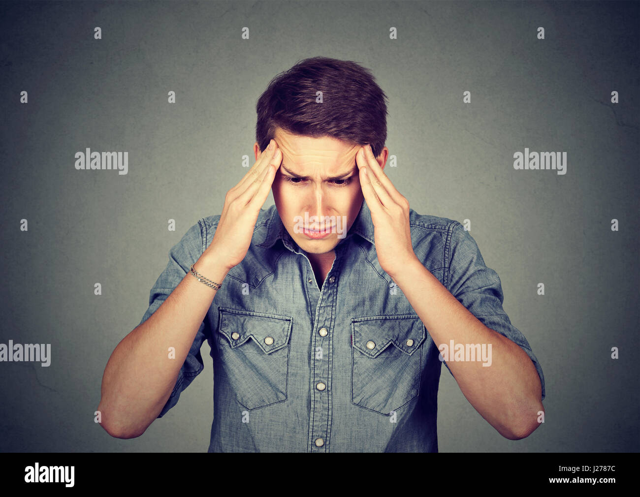 Betont Man mit Kopfschmerzen auf graue Wand Hintergrund isoliert Stockfoto