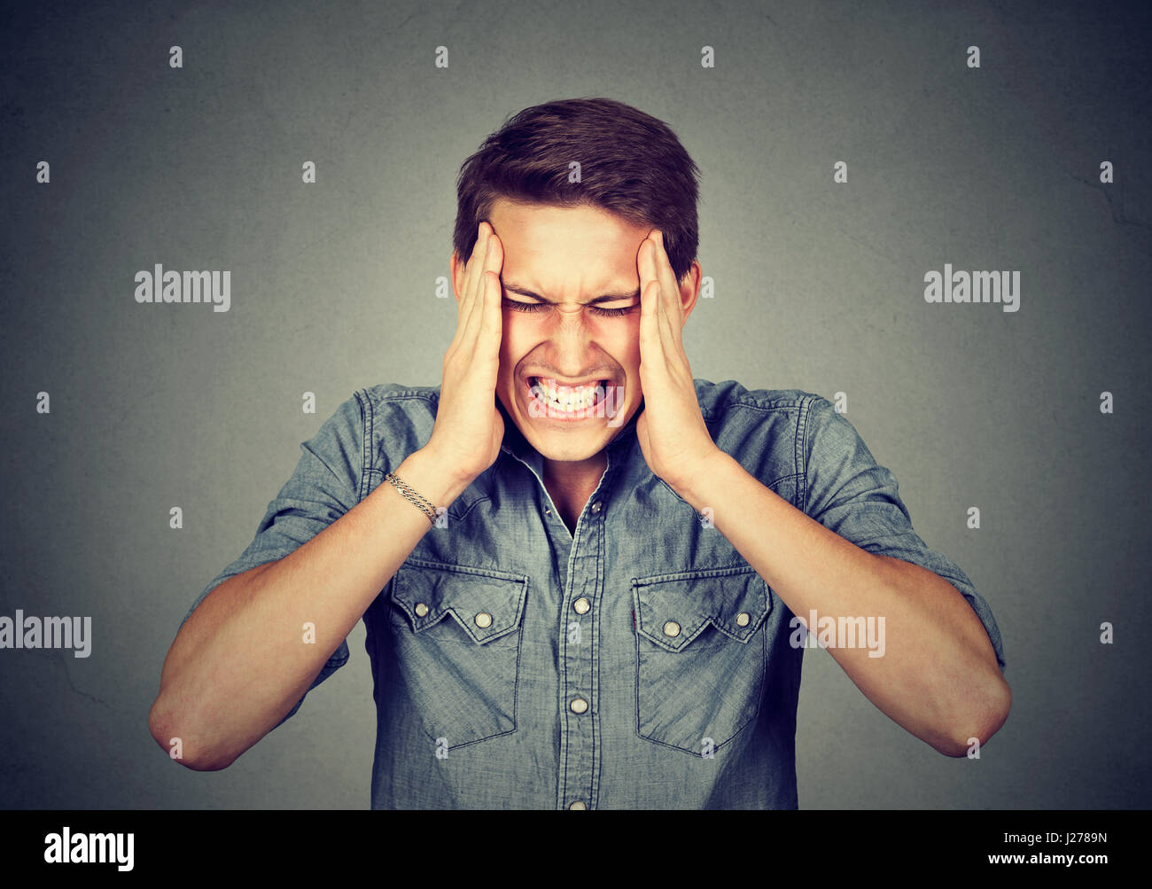 Gestressten Mann mit Kopfschmerzen auf graue Wand Hintergrund isoliert Stockfoto
