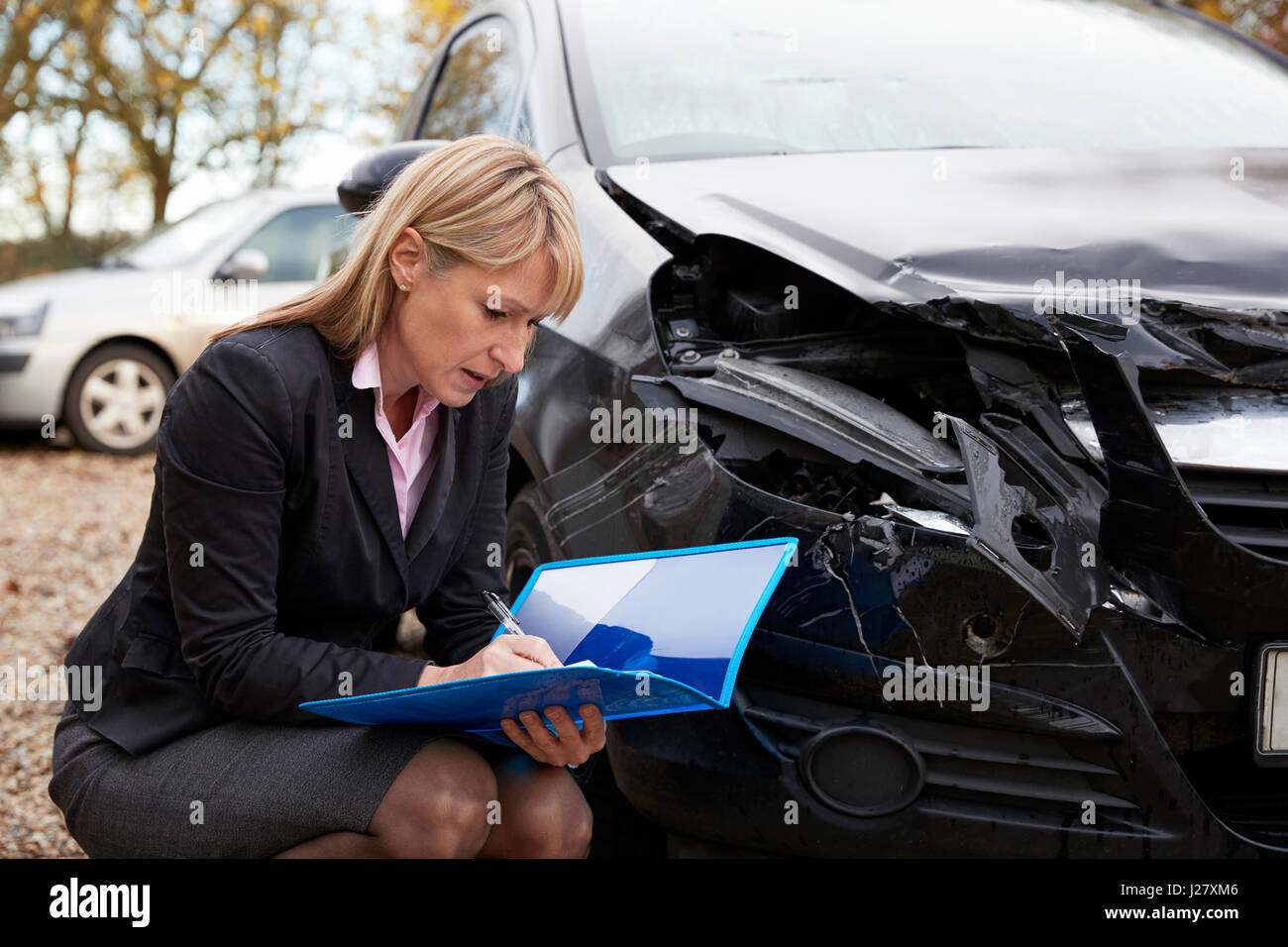 Weiblich Loss Adjuster schriftlich Bericht über beschädigtes Auto Stockfoto