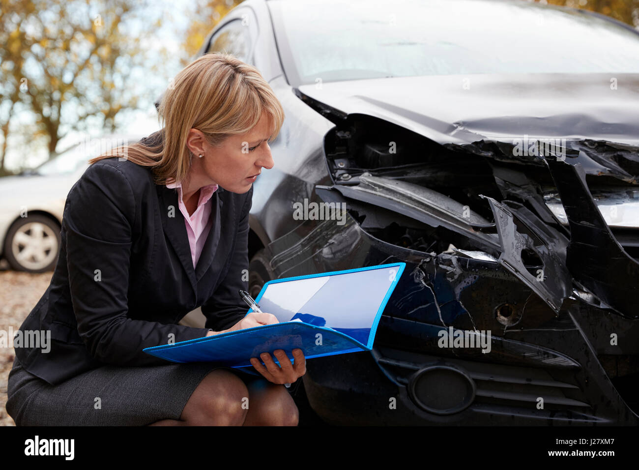 Weiblich Loss Adjuster schriftlich Bericht über beschädigtes Auto Stockfoto