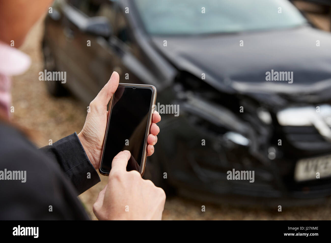 Loss Adjuster Aufnahme des beschädigten Autos auf Handy Stockfoto