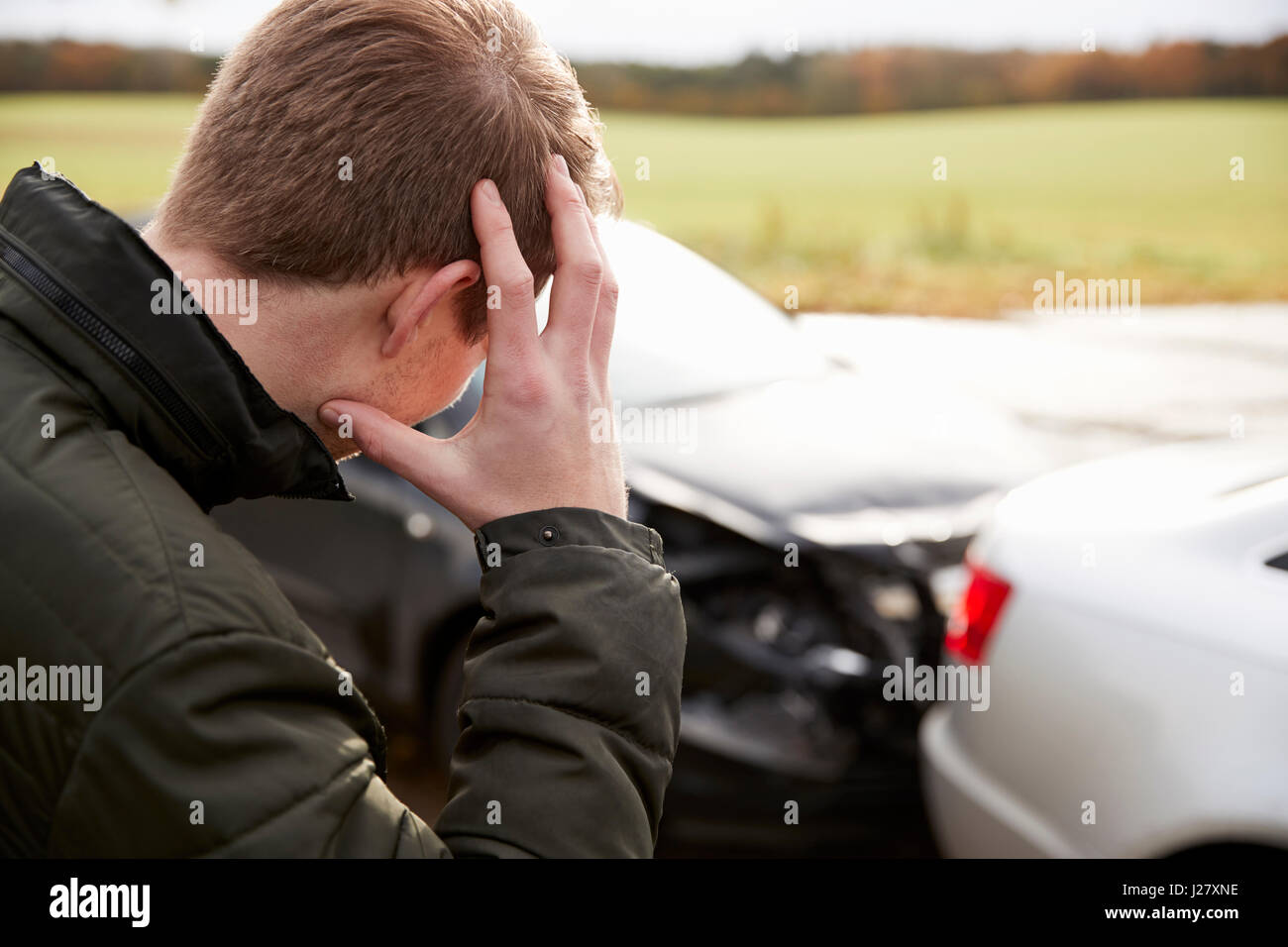 Frustriert Mann mit beschädigtem Auto nach Unfall Stockfoto