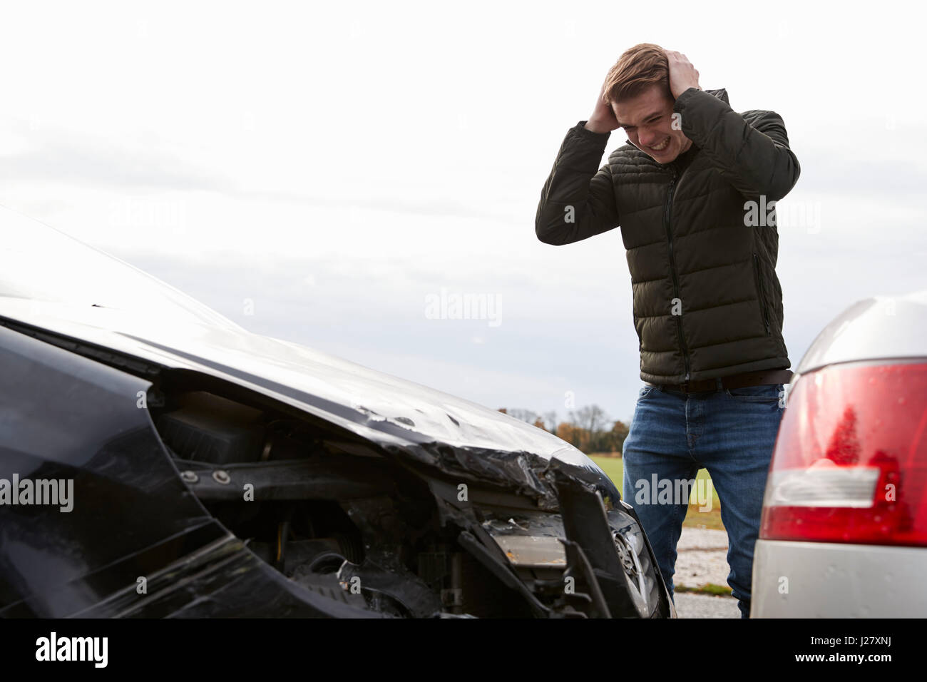 Frustriert Mann mit beschädigtem Auto nach Unfall Stockfoto