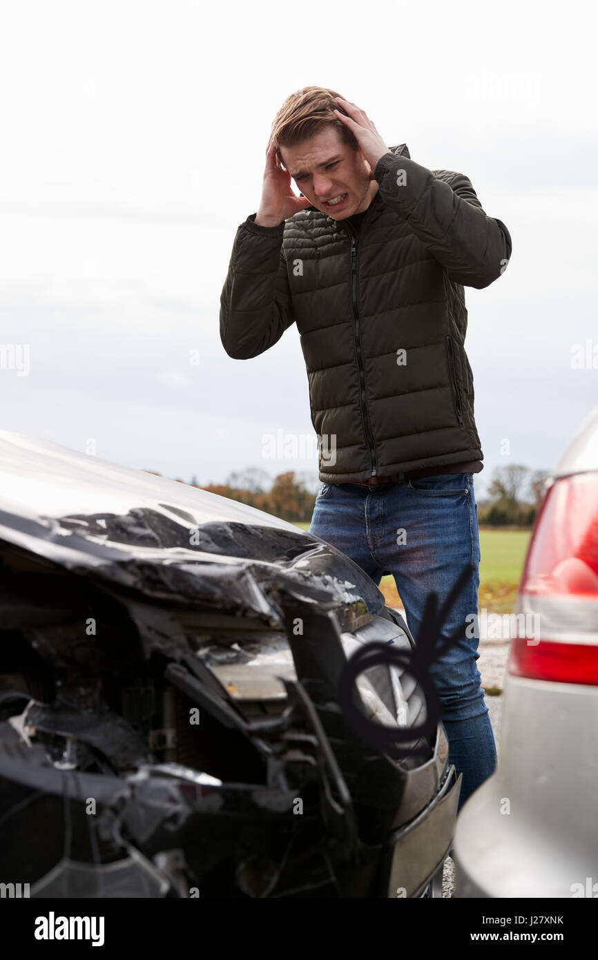Frustriert Mann mit beschädigtem Auto nach Unfall Stockfoto