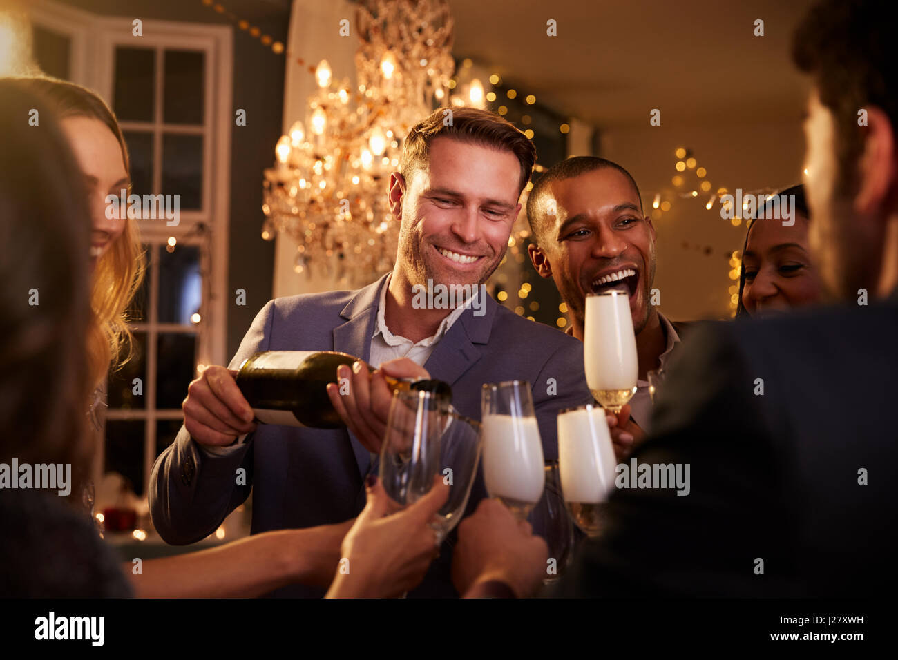 Freunde, Champagner zu öffnen, wie sie auf Party zusammen feiern Stockfoto