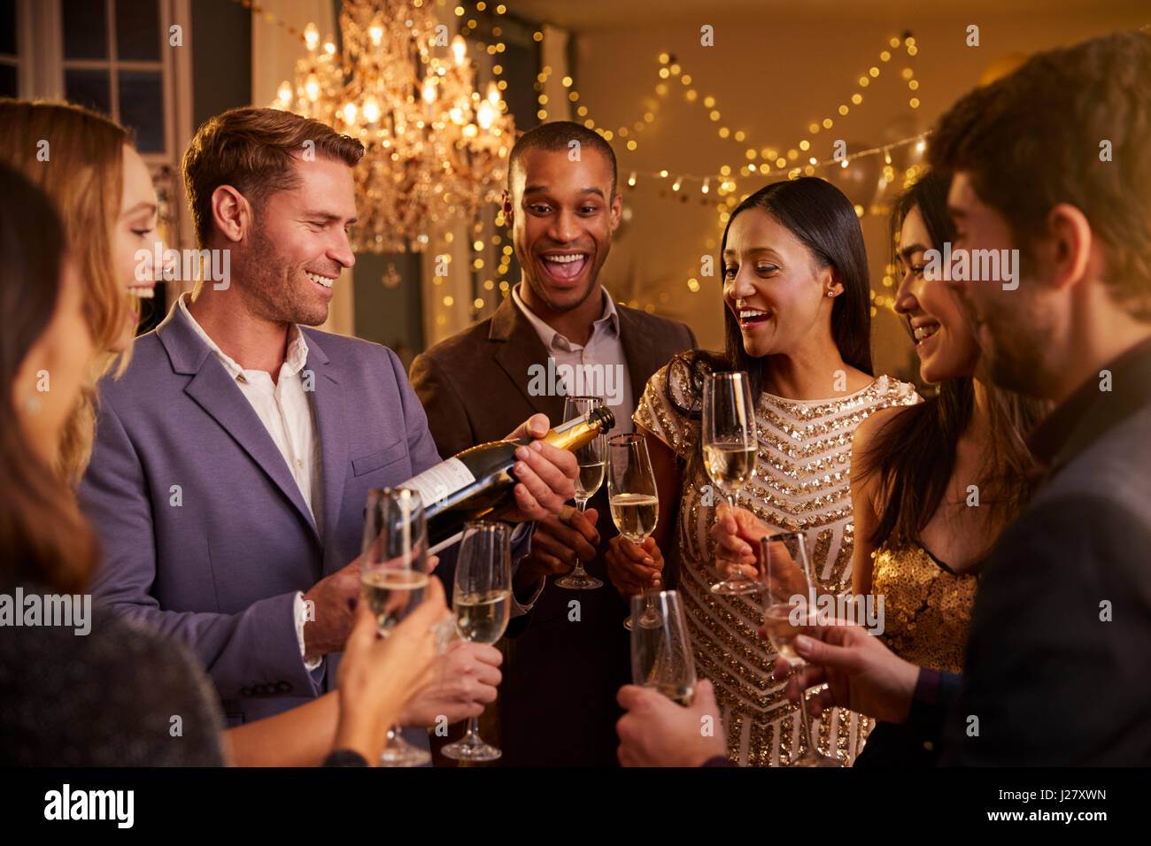 Freunde, Champagner zu öffnen, wie sie auf Party zusammen feiern Stockfoto
