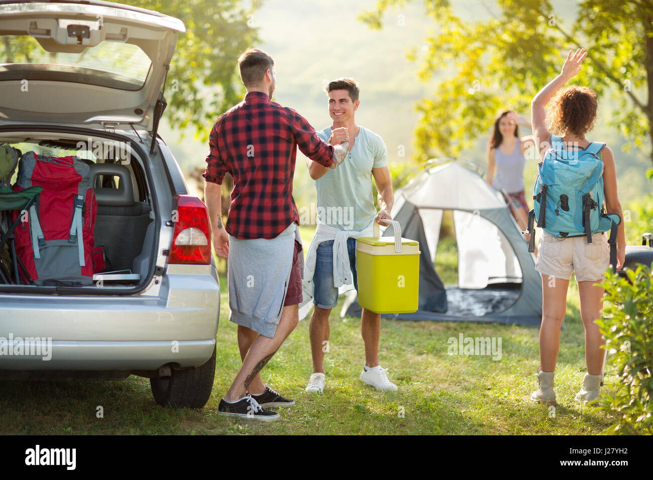 Junge glückliche Paar auf camping-Ausflug Hallo zu sagen kam Freunde Stockfoto